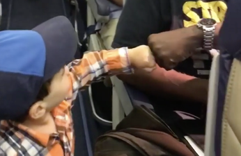 Adorable toddler fist bumping his way onto a flight will brighten your day