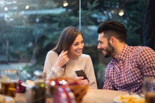 Couple dating and looking at something on a cellphone.