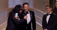 Tommy Wiseau tries to grab the mic after James Franco’s Golden Globes win