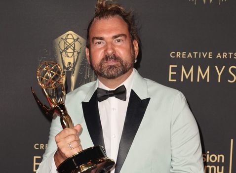 Makeup artist Marc Pilcher holds his Emmy award on the red carpet.