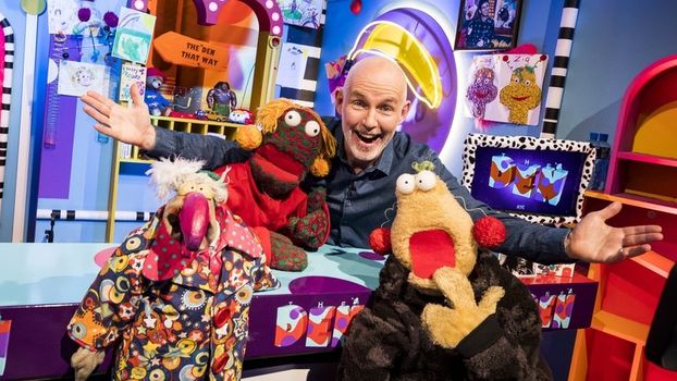 A still from The Den. Host Ray D'Arcy stands with his arms over three puppets.
